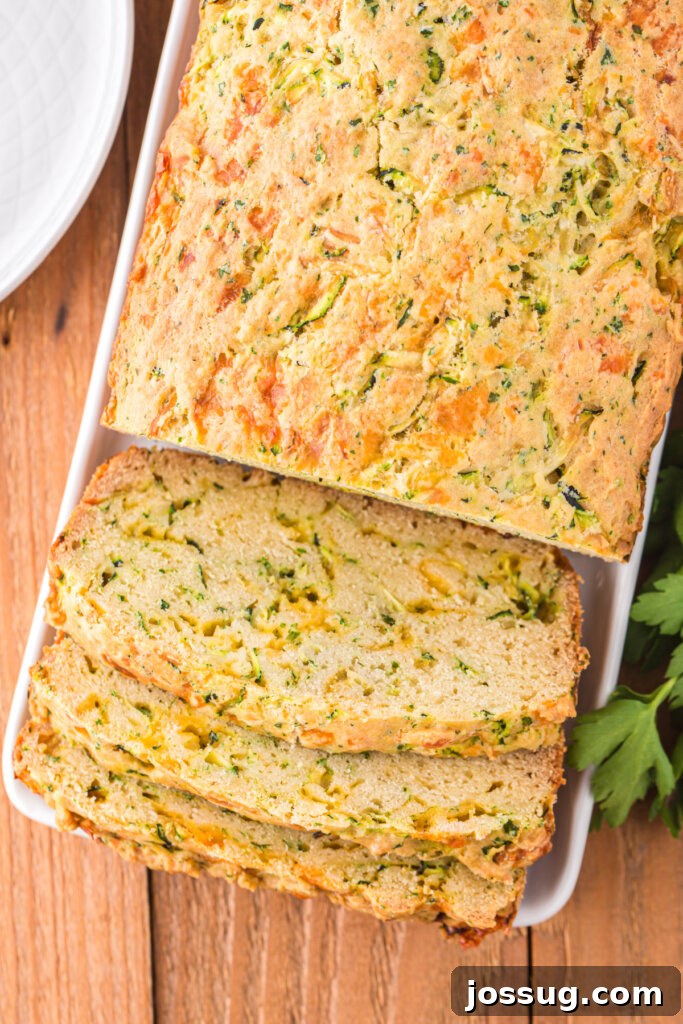 Savory Zucchini Cheese Loaf 5 A complete loaf of cheesy zucchini bread on a cutting board, with several slices already cut, revealing the cheesy, moist interior.