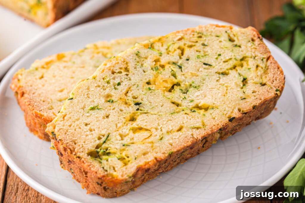 Savory Zucchini Cheese Loaf 6 Two perfectly cut slices of cheesy zucchini bread on a small white plate, ready to be enjoyed.