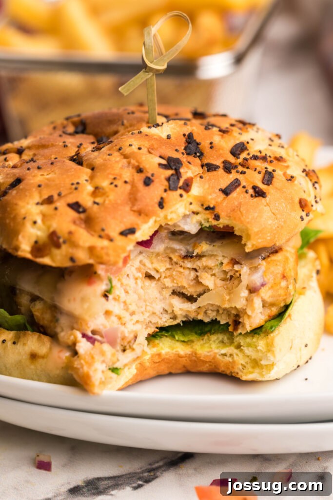 Explosive Bang-Bang Chicken Burgers 3 A delicious chicken burger with Bang-Bang sauce, cut in half to showcase its juicy patty and fresh toppings.