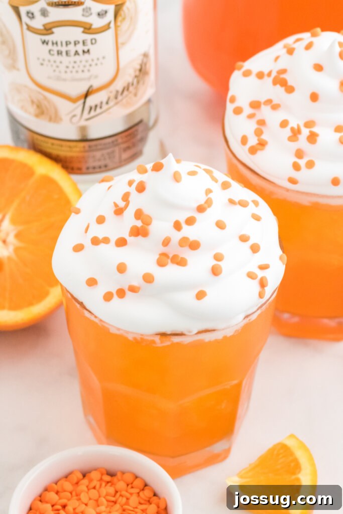 orange creamsicle cocktail garnished with whipped cream and orange sprinkles