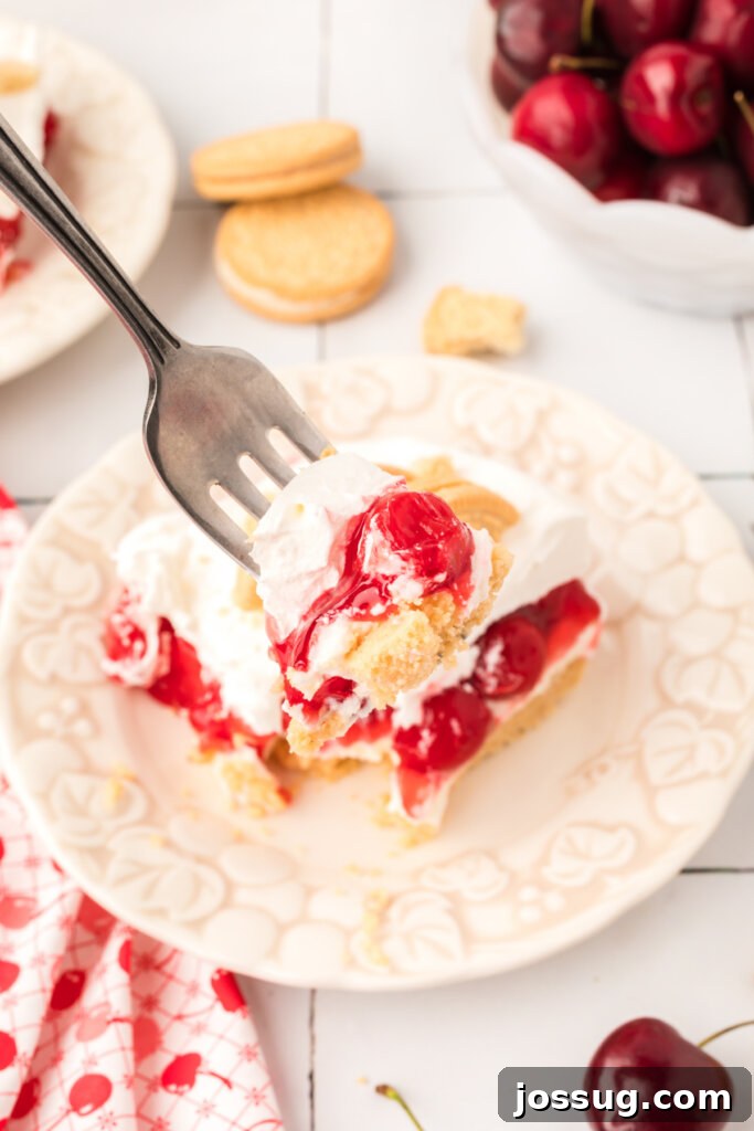 A fork scooping a generous bite of Cherry Lasagna Lush, showing the distinct layers of golden crust, white cream cheese, and red cherry filling, highlighting its enticing texture.