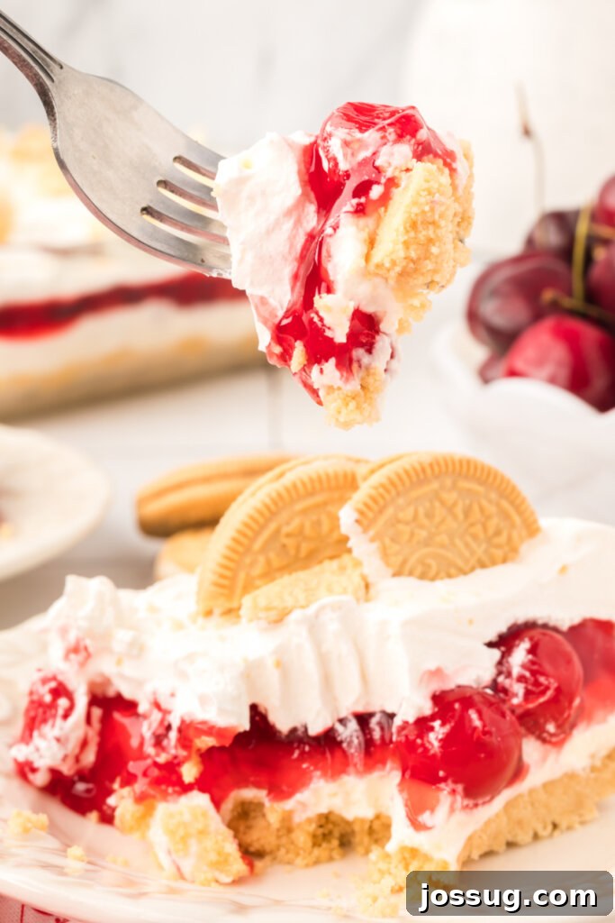 A close-up shot of a single bite of Cherry Lasagna Lush on a fork, showing the distinct layers and the smooth, creamy texture of the dessert, ready to be enjoyed.