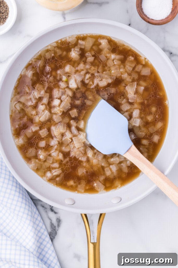 Warm German potato salad dressing simmering in a skillet, showcasing the rich, tangy liquid base before combining with potatoes.
