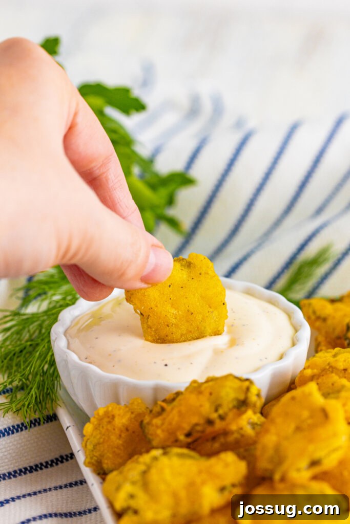 hand dipping a fried pickle into ranch dressing