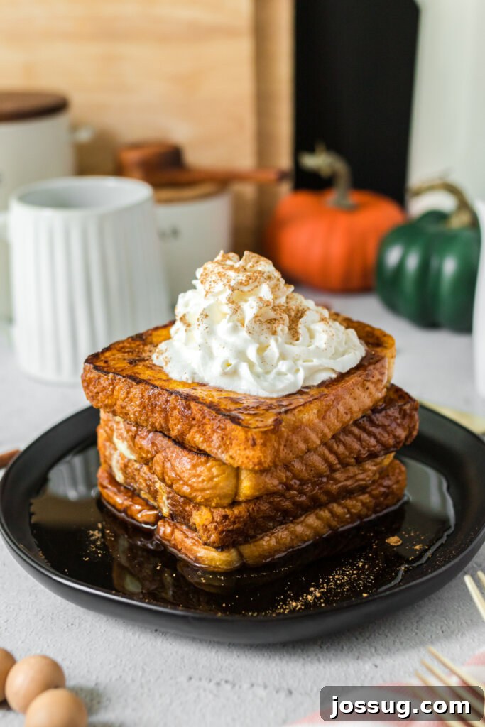 Stack of golden-brown pumpkin spice French toast slices drizzled with syrup on a white plate, ready to be served.