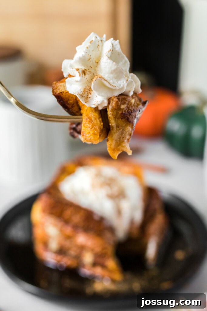 A fork holding a bite of pumpkin spice French toast, showing the fluffy texture and warm, inviting colors.
