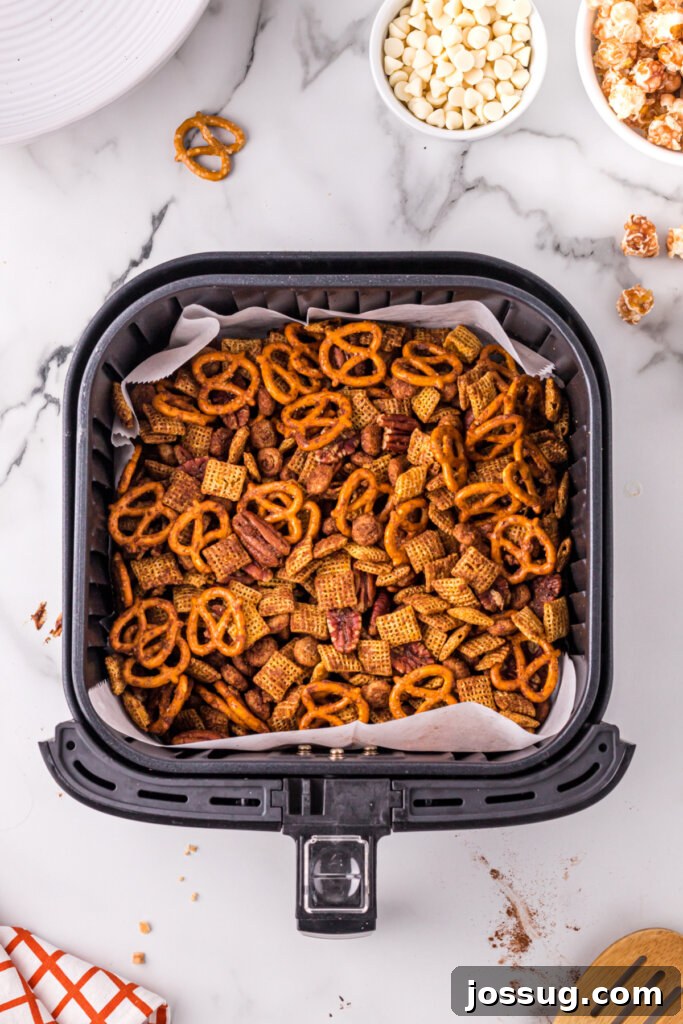 Crispy Autumn Air Fryer Snack Mix 4 Raw ingredients for Air Fryer Fall Chex Mix coating the bottom of an air fryer basket, ready for cooking.