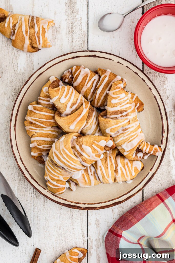Sweet Cinnamon Crescents 2 freshly baked cinnamon crescent rolls on a plate, golden brown and glistening with glaze