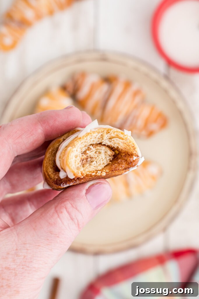 Sweet Cinnamon Crescents 3 hand holding a cinnamon crescent roll showing the warm, gooey interior