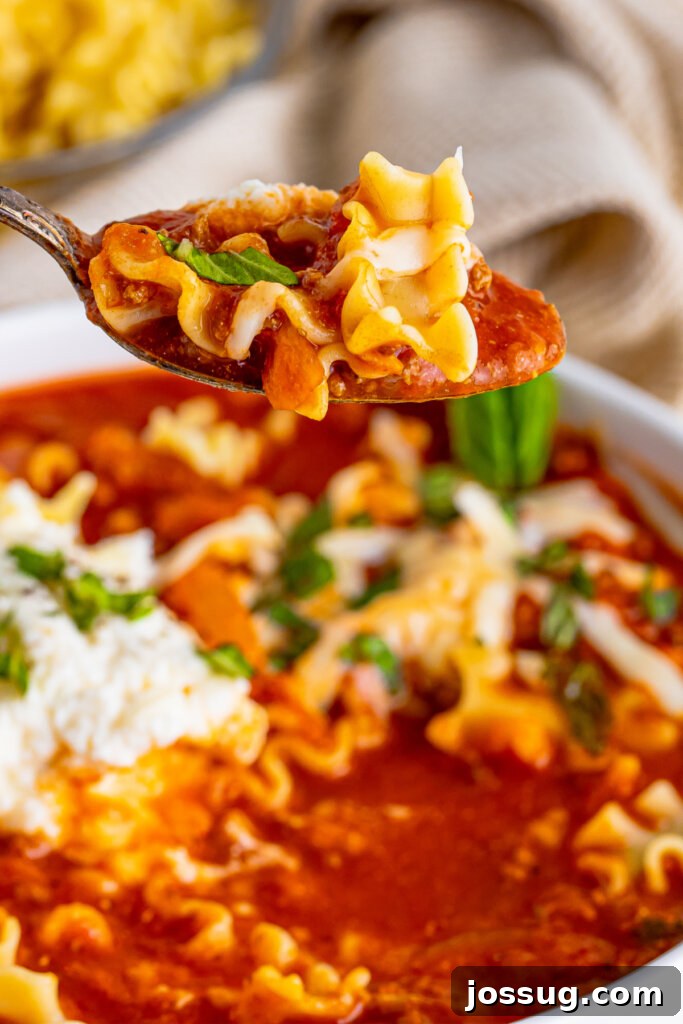 Lasagna in a Bowl 4 A spoon with a perfect bite of lasagna soup, highlighting the combination of pasta, cheese, and meat.