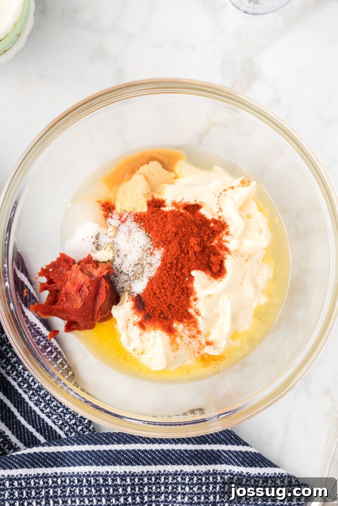 Irresistible Dipping Sauce 4 Bowls of individual ingredients for Yum Yum Sauce laid out on a table, including mayonnaise, tomato paste, melted butter, granulated sugar, rice vinegar, paprika, garlic powder, and salt and pepper.
