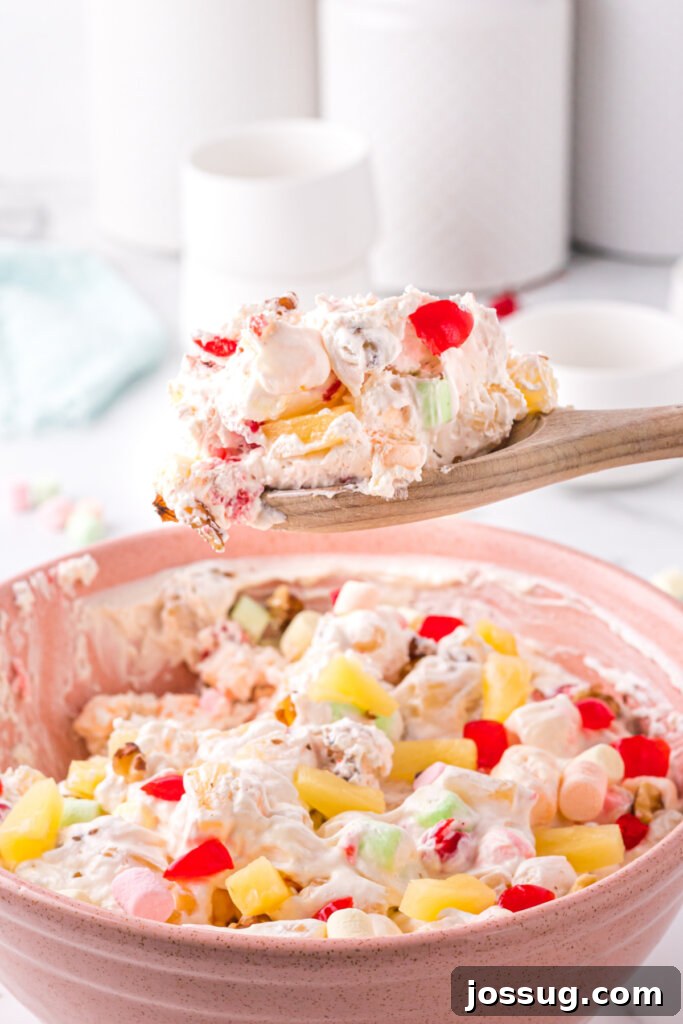 wooden spoon scooping pineapple fluff salad from bowl