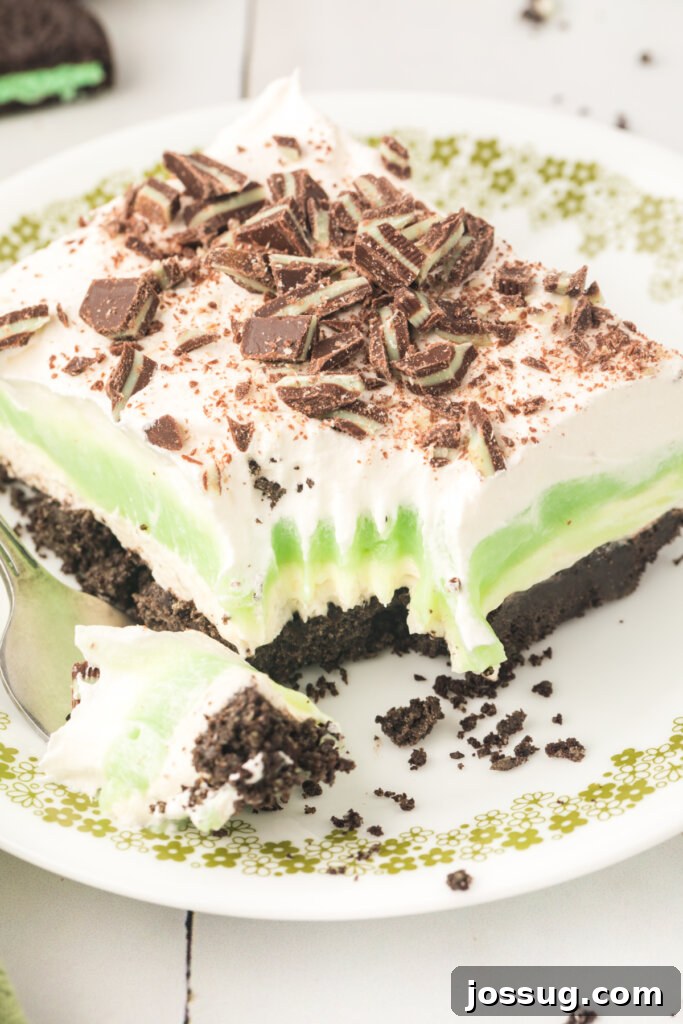 Layers of Luxe: Grasshopper Lasagna 4 A close-up shot of a single slice of Grasshopper Lasagna Lush on a plate, with a fork taking a bite, showing the perfect layering.