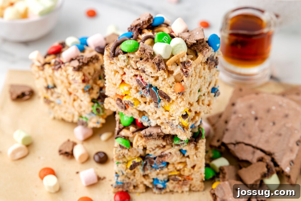Buddy's Happy Holiday Crispy Treats 6 A festive stack of colorful Christmas Rice Krispies Treats, adorned with holiday sprinkles and chocolate, on a white plate.