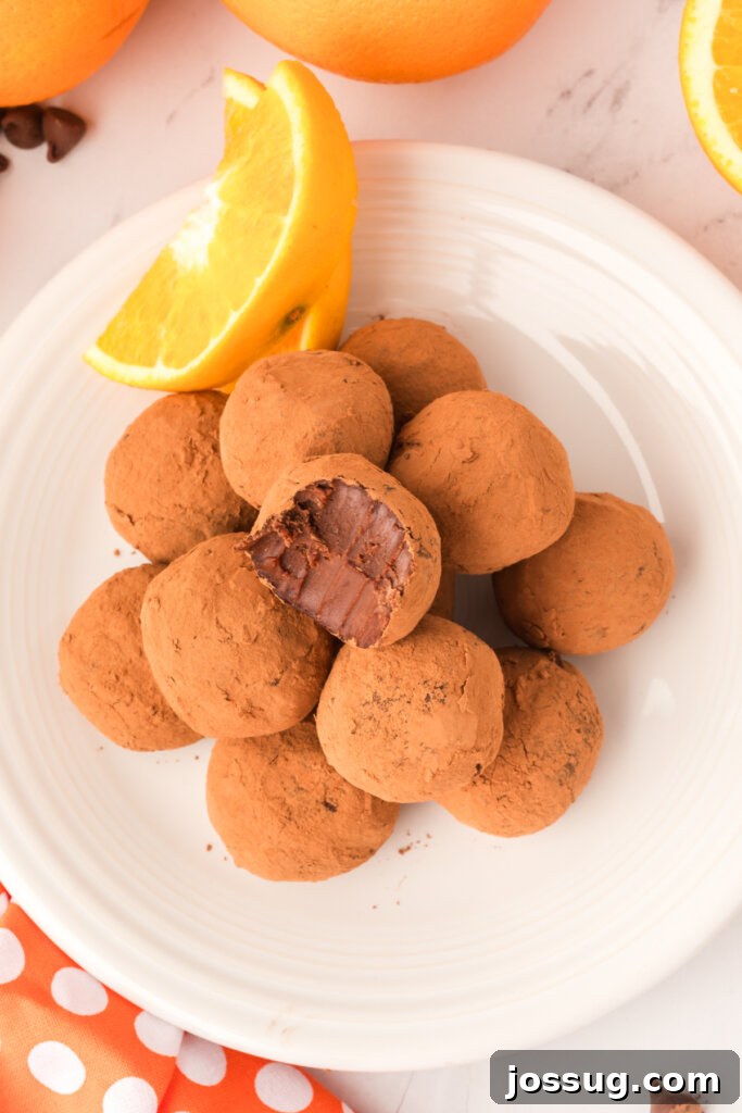 A plate filled with an assortment of chocolate orange truffles, some dusted with cocoa