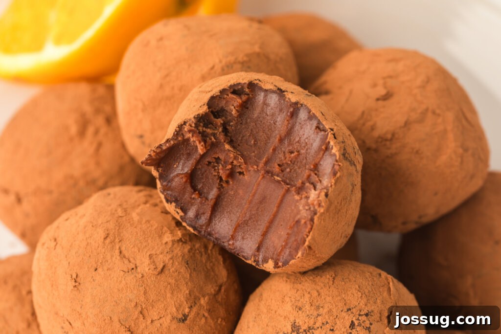 Close-up of a chocolate orange truffle cut in half, revealing its smooth, rich interior