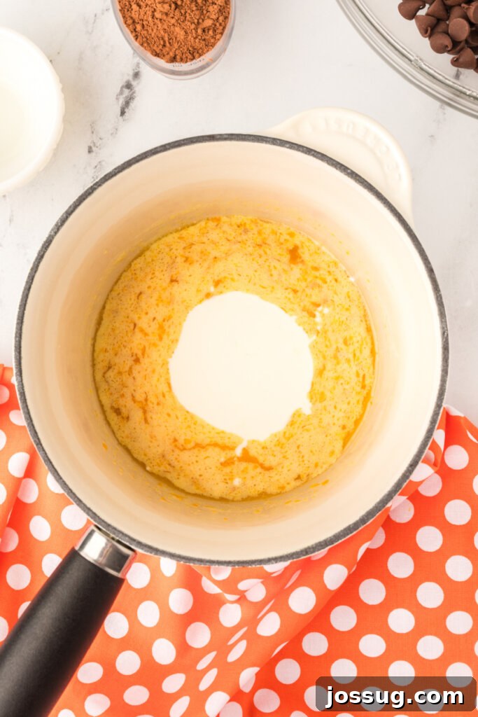 Heavy cream being added to the melted butter and orange zest mixture