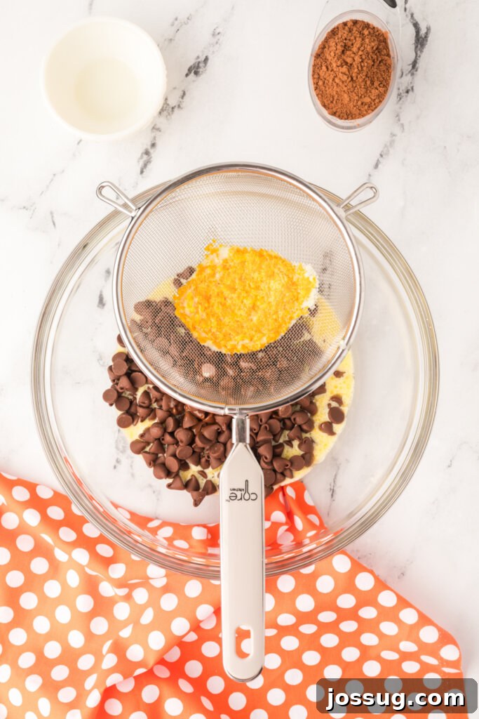 Straining the hot cream mixture through a fine mesh sieve over chocolate chips