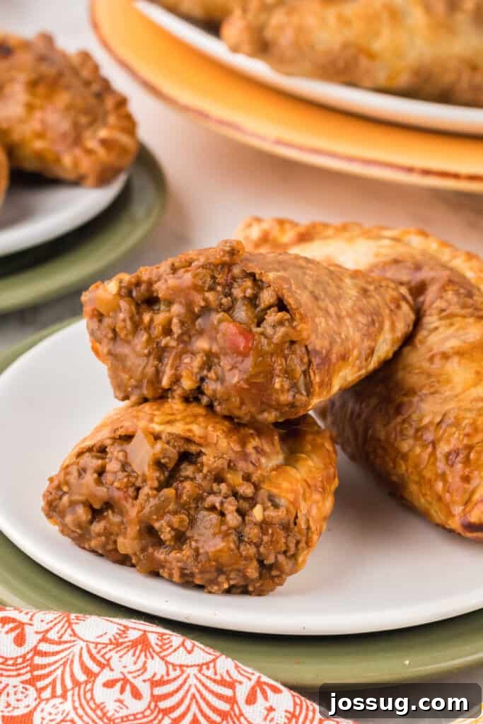 Crispy Air-Fried Beef Empanadas 14 A single beef empanada perfectly sliced in half, showcasing its rich filling and crispy crust on a white plate