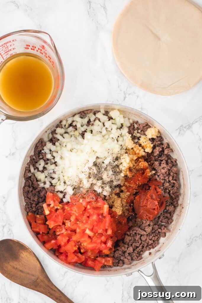 Crispy Air-Fried Beef Empanadas 6 Add diced onion, minced garlic, tomato paste, tomatoes, cumin, chili powder, paprika salt, and pepper to the skillet with the ground beef. Cook for an additional 2-3 minutes until the onion is softened.