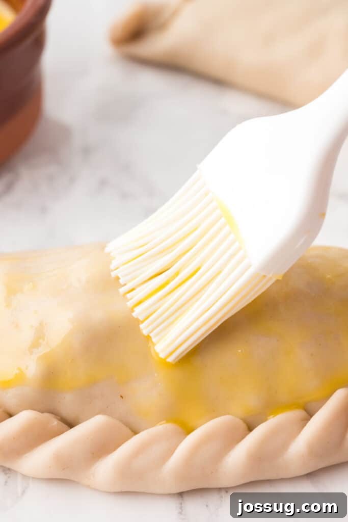 Crispy Air-Fried Beef Empanadas 10 A pastry brush applying egg wash on top of each empanada