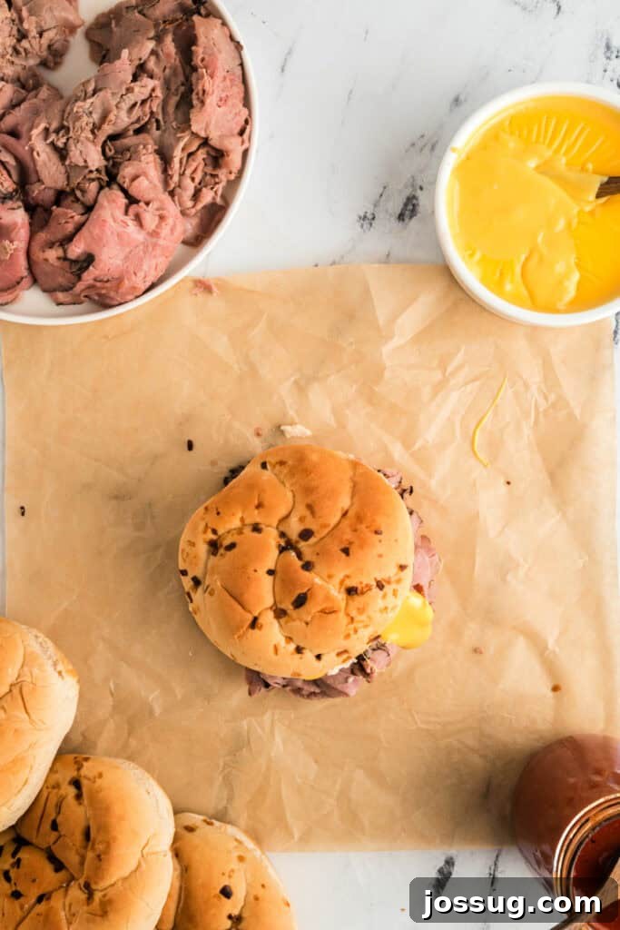 Carefully placing the top bun onto the fully loaded Arby's Beef and Cheddar sandwich.