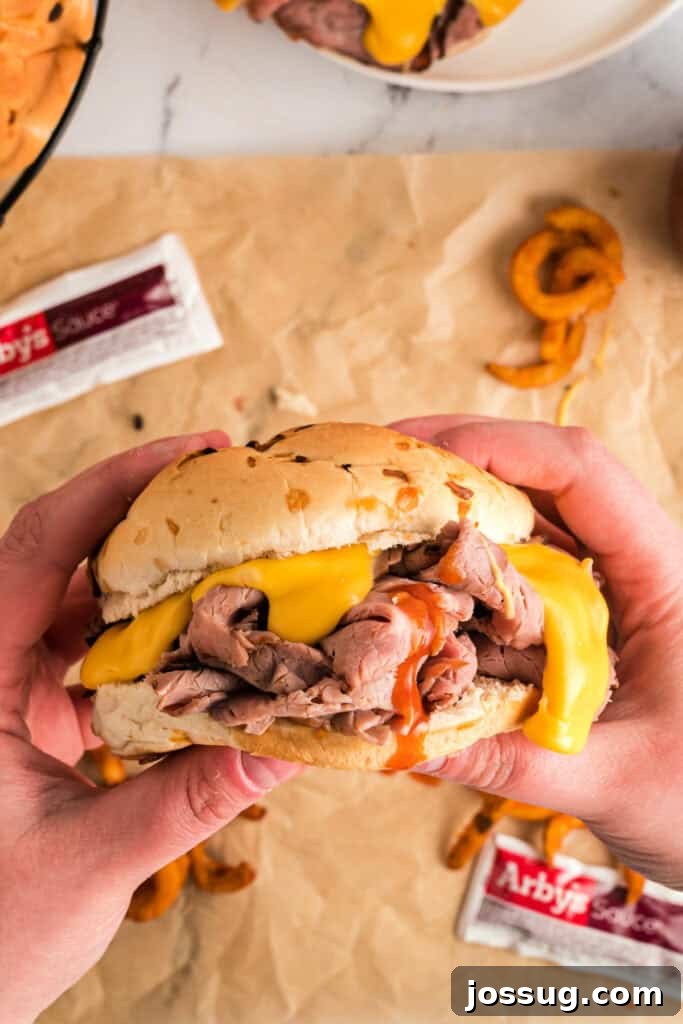 A finished, ready-to-eat copycat Arby's Beef and Cheddar sandwich, glistening with cheese sauce.