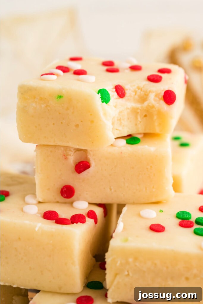 Frosted Sugar Cookie Fudge 2 Closeup of stacked sugar cookie fudge squares, adorned with festive sprinkles, showcasing their creamy texture and inviting appearance, perfect for holiday gatherings and gifting