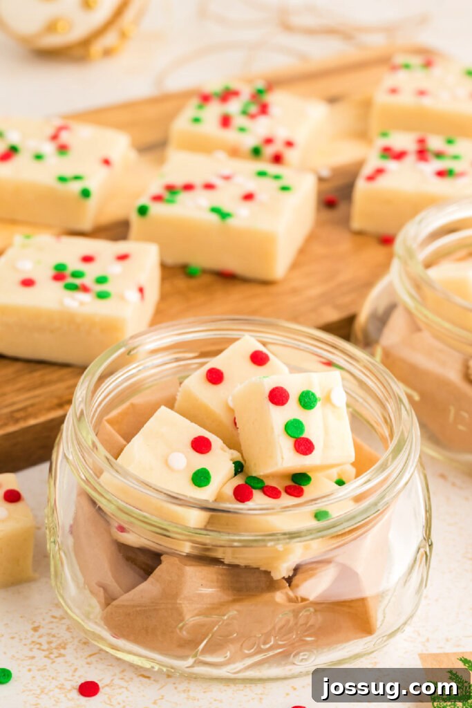 Frosted Sugar Cookie Fudge 4 Individual pieces of vibrant sugar cookie fudge, adorned with colorful Christmas sprinkles, neatly presented in a clear glass jar
