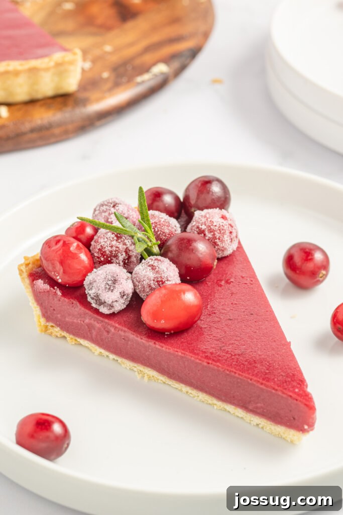 a slice of cranberry curd tart on a white plate, garnished with cranberries