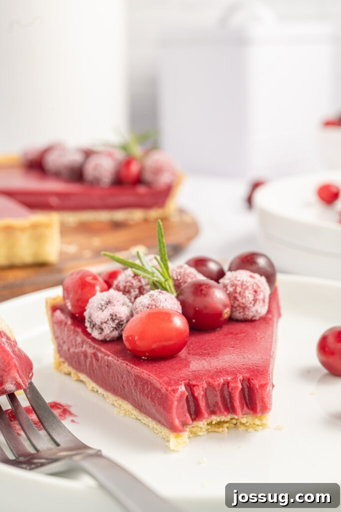 slice of cranberry curd tart with a bite missing, showcasing its layers