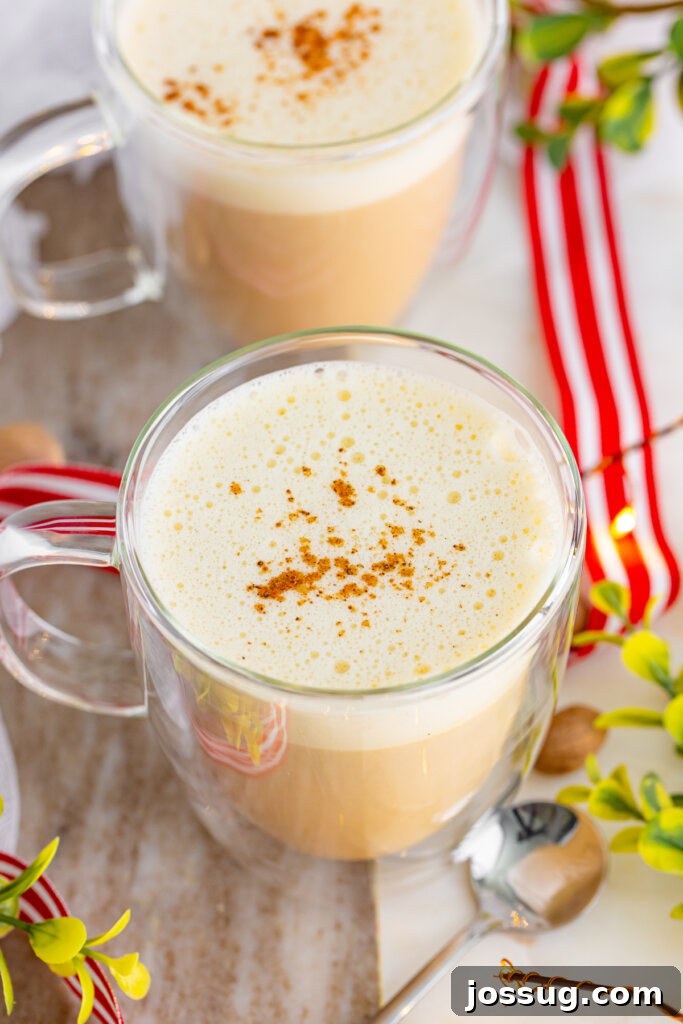Yuletide Velvet Latte 3 An overhead shot looking down into a clear mug filled with a rich eggnog latte, topped with frothy milk and a dusting of nutmeg.