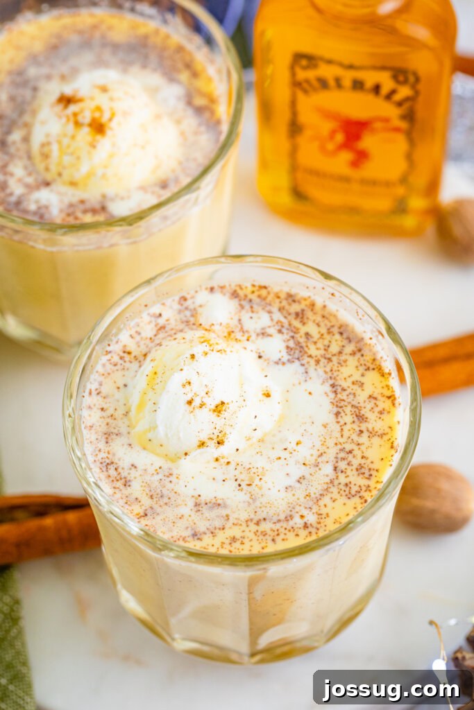 Holiday Eggnog Cheer 2 two glasses filled with eggnog punch and fireball whiskey in the background