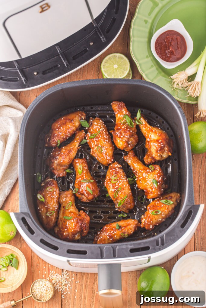 Sticky Honey Sriracha Wings 3 Close-up view of freshly cooked honey sriracha wings in an air fryer basket, demonstrating their crispy texture and golden-brown finish.