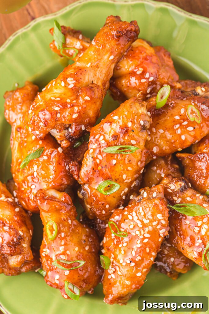 Sticky Honey Sriracha Wings 4 A close-up shot of several honey sriracha wings, perfectly glazed and garnished, arranged on a green plate, highlighting their appetizing appearance.