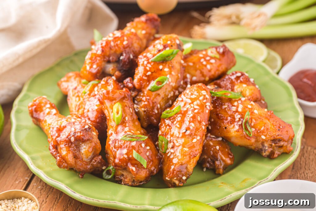 Sticky Honey Sriracha Wings 7 A vibrant display of cooked honey sriracha wings, generously coated in sauce and garnished, arranged on a green plate, ready to be enjoyed.