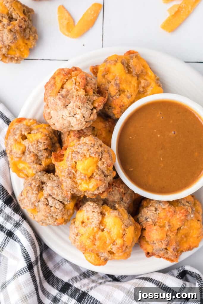Cheesy Sausage Balls 2 Delicious golden brown sausage balls served on a plate with an accompanying dipping sauce.