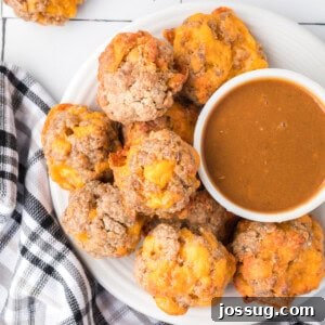 Closeup of freshly baked sausage balls served with a dipping sauce on a plate.
