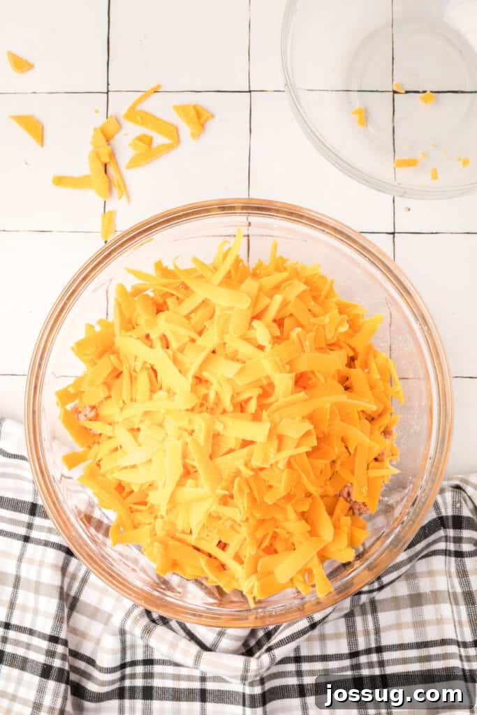 Cheesy Sausage Balls 6 Shredded cheddar cheese being added to the mixed sausage and biscuit ingredients.