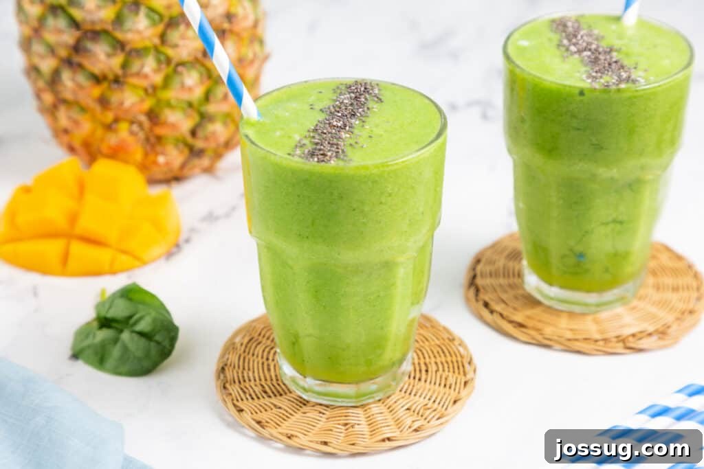 two pineapple green smoothies in glasses with fresh fruit on the side, ready to be enjoyed