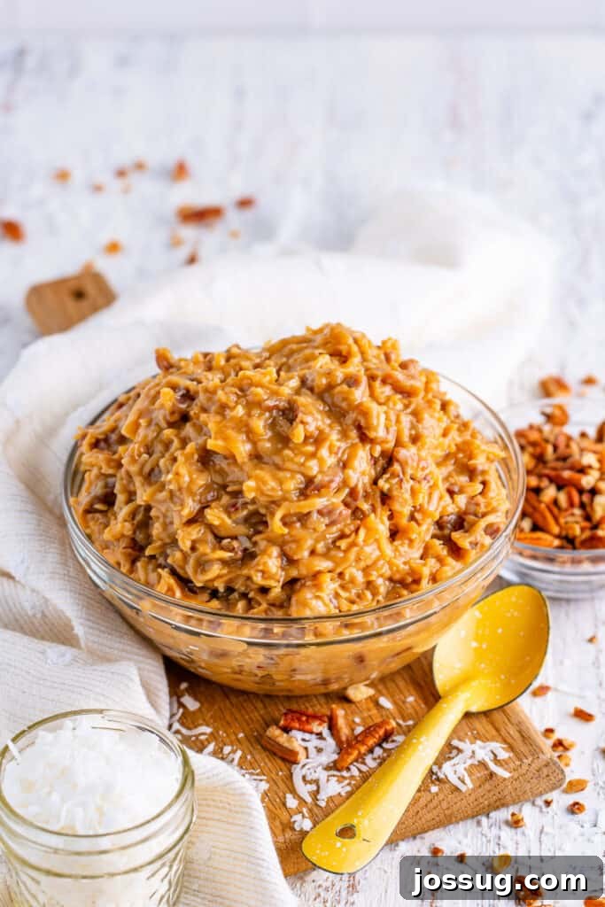 Toasted Coconut Pecan Frosting 2 Homemade Coconut Pecan Frosting in a bowl, showing its thick, creamy texture and visible pieces of coconut and pecan, ready to be spread on a cake or cupcakes.