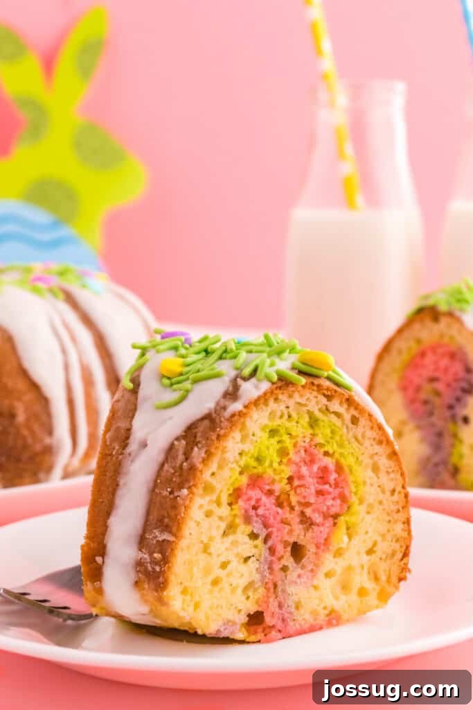 Slice of Easter Swirl Bundt Cake on a plate, showcasing the vibrant green, pink, and purple swirls inside