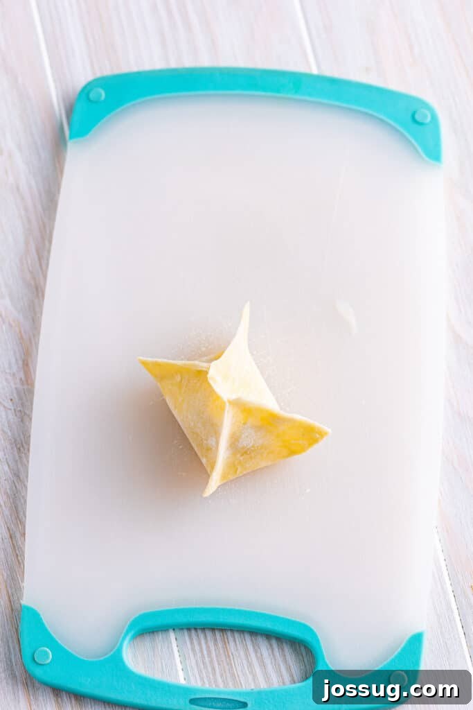 Crispy Crab Clouds 12 Repeat with the other two corners and push out as much air as possible while pinching all the seams together well to form a package. Repeat with the remaining filling and wrappers and place them on a sheet tray.