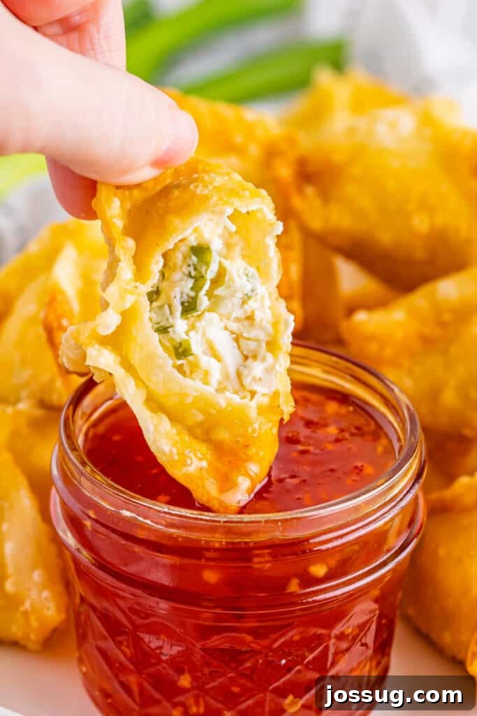 Crispy Crab Clouds 16 crab rangoon open to show the inside being dipped into sweet chili sauce