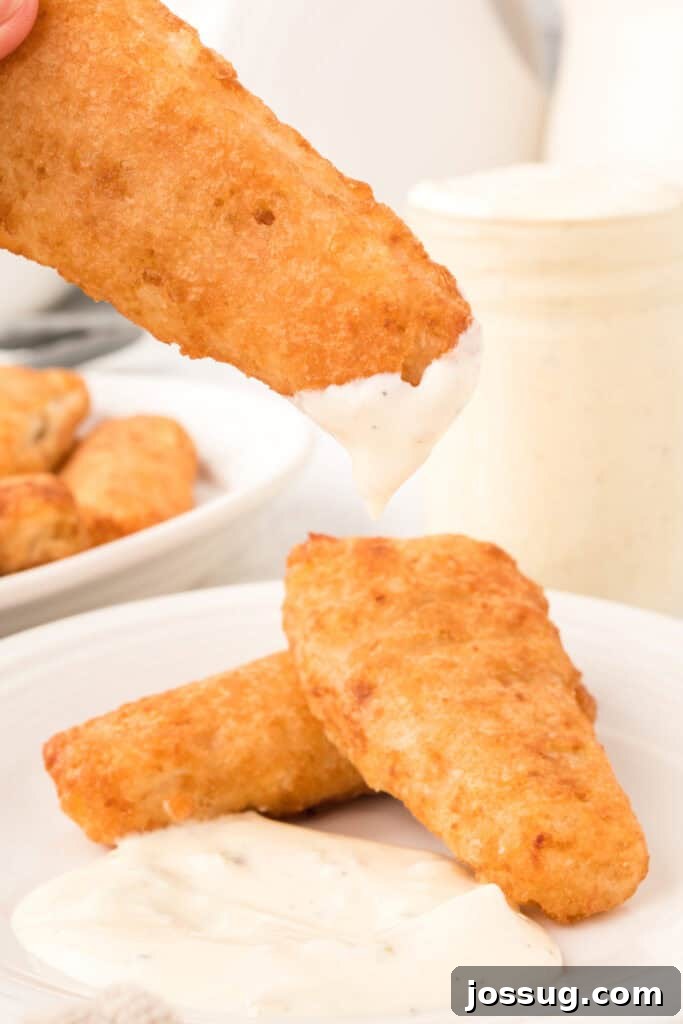 Creamy Dill & Caper Dressing 8 Fried fish portions being delicately dipped into a bowl of creamy tartar sauce.