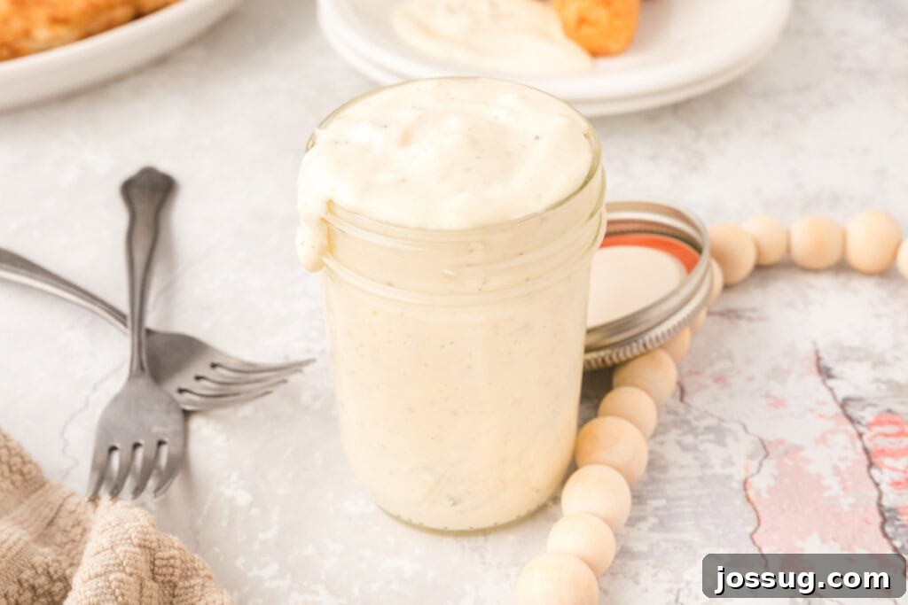 Creamy Dill & Caper Dressing 9 Tartar sauce in a elegant glass jar, garnished with crisscrossed forks and decorative beads nearby.