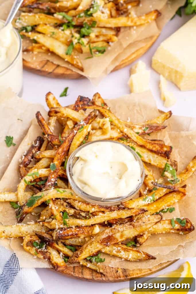 Crispy garlic parmesan fries artistically arranged in a circle around a small white bowl of creamy garlic aioli, showcasing their golden-brown perfection.