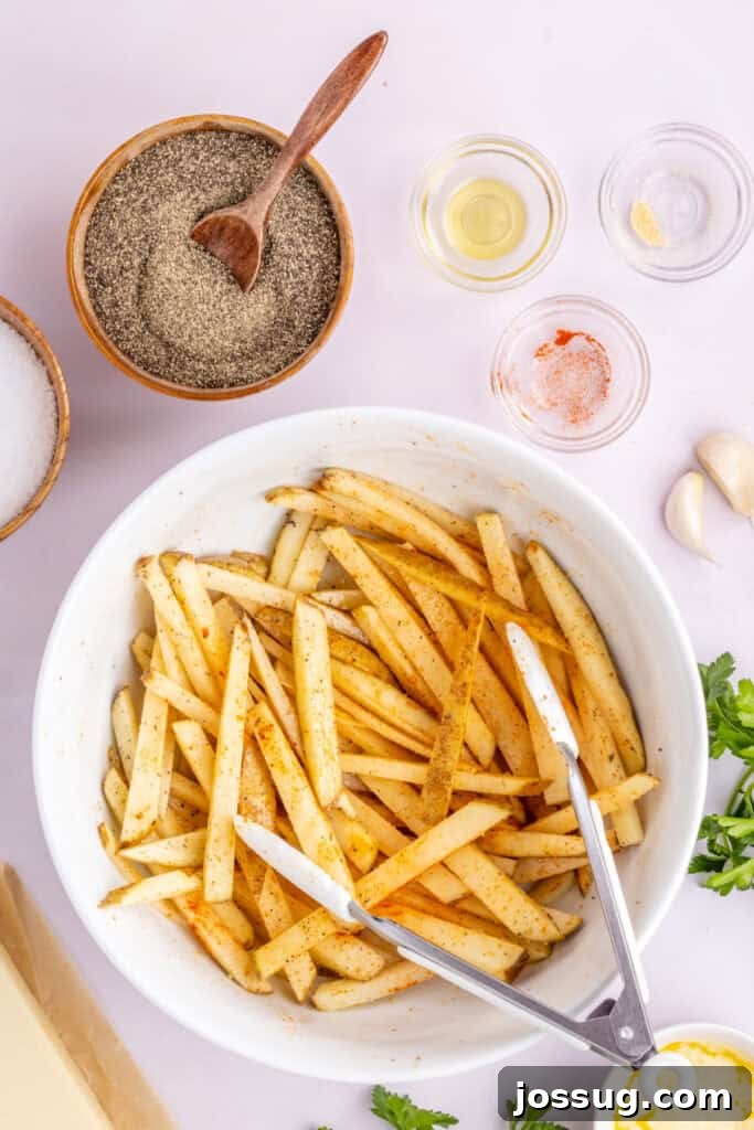 Step 3: Close-up of seasoned fries being tossed with tongs in a bowl, ensuring full coating before air frying.