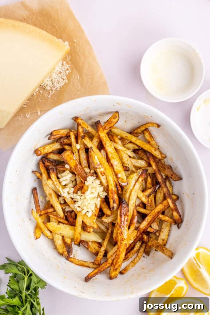 Step 5: Partially cooked fries are returned to the mixing bowl, where melted butter and minced garlic have been added, ready to be tossed.