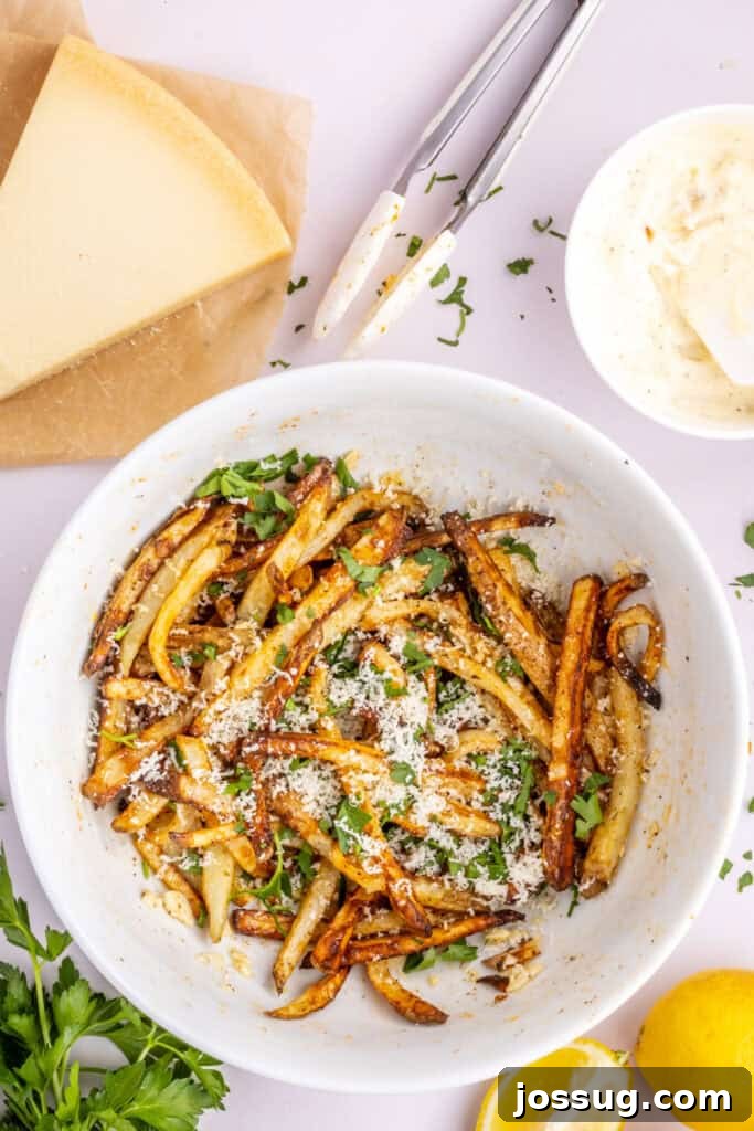 Step 6: Cooked garlic parmesan fries are sprinkled with grated Parmesan cheese and chopped fresh parsley, ready for a final gentle toss and immediate serving.